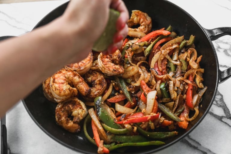 Squeezing lime juice into pan of shrimp fajitas