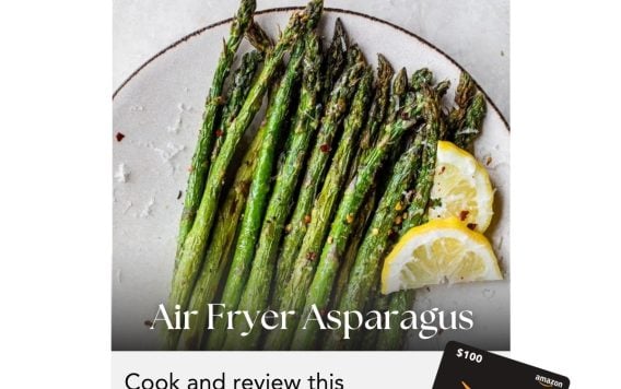 A plate of air fryer asparagus with lemon slices, promoting an April cooking challenge to win a $100 Amazon gift card.