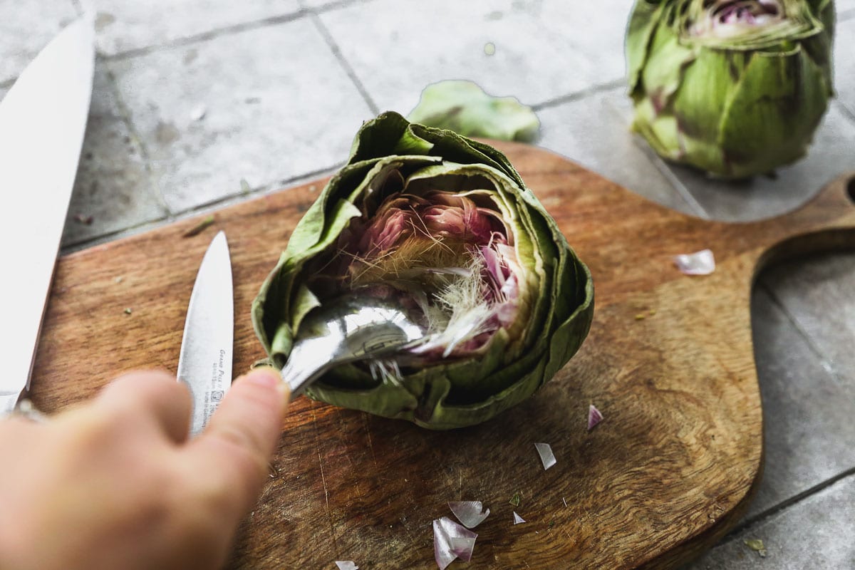 Spoon scooping choke from center of artichoke