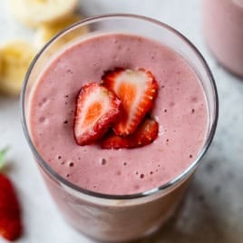 Strawberry banana smoothie in glass with strawberry slices on top