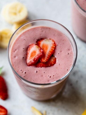 Strawberry banana smoothie in glass with strawberry slices on top