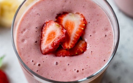 Strawberry banana smoothie in glass with strawberry slices on top