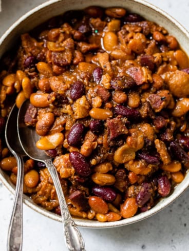 Overhead view of crockpot baked beans in bowl with two spoons