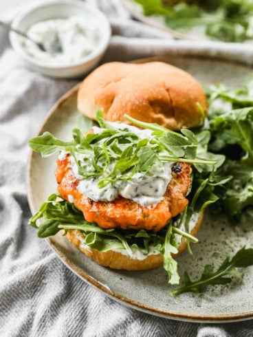 Salmon burger topped with yogurt herb sauce and arugula