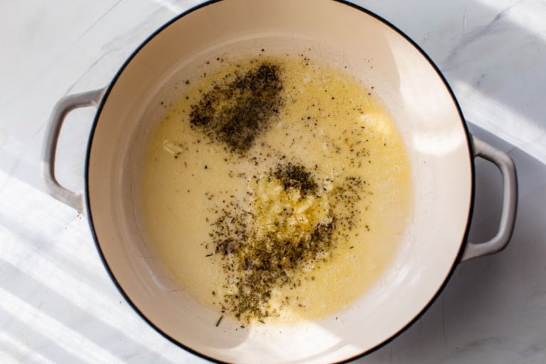 Butter, Italian seasoning, and garlic cooking in Dutch oven