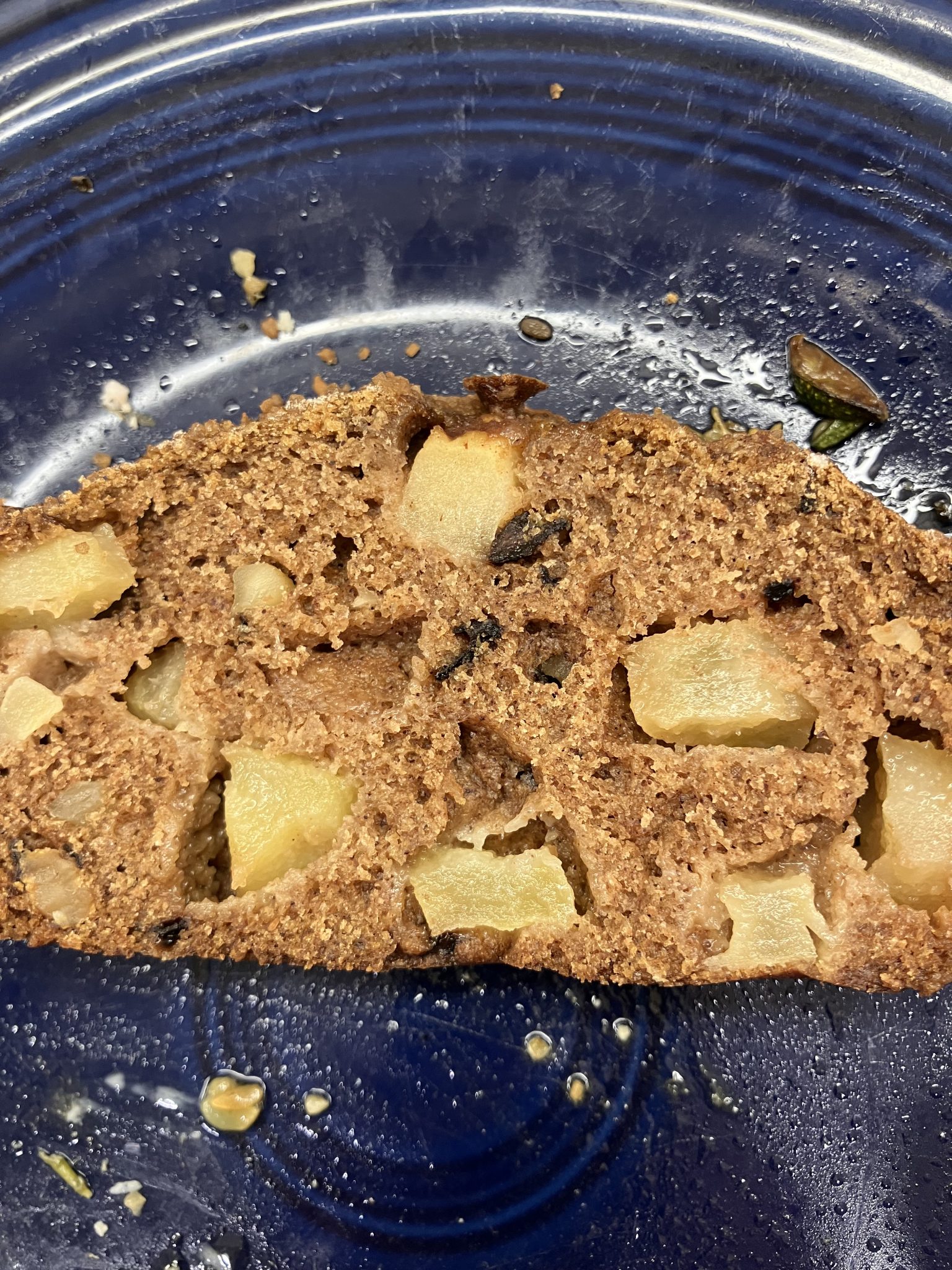 A slice of apple bread with visible apple chunks on a blue plate.