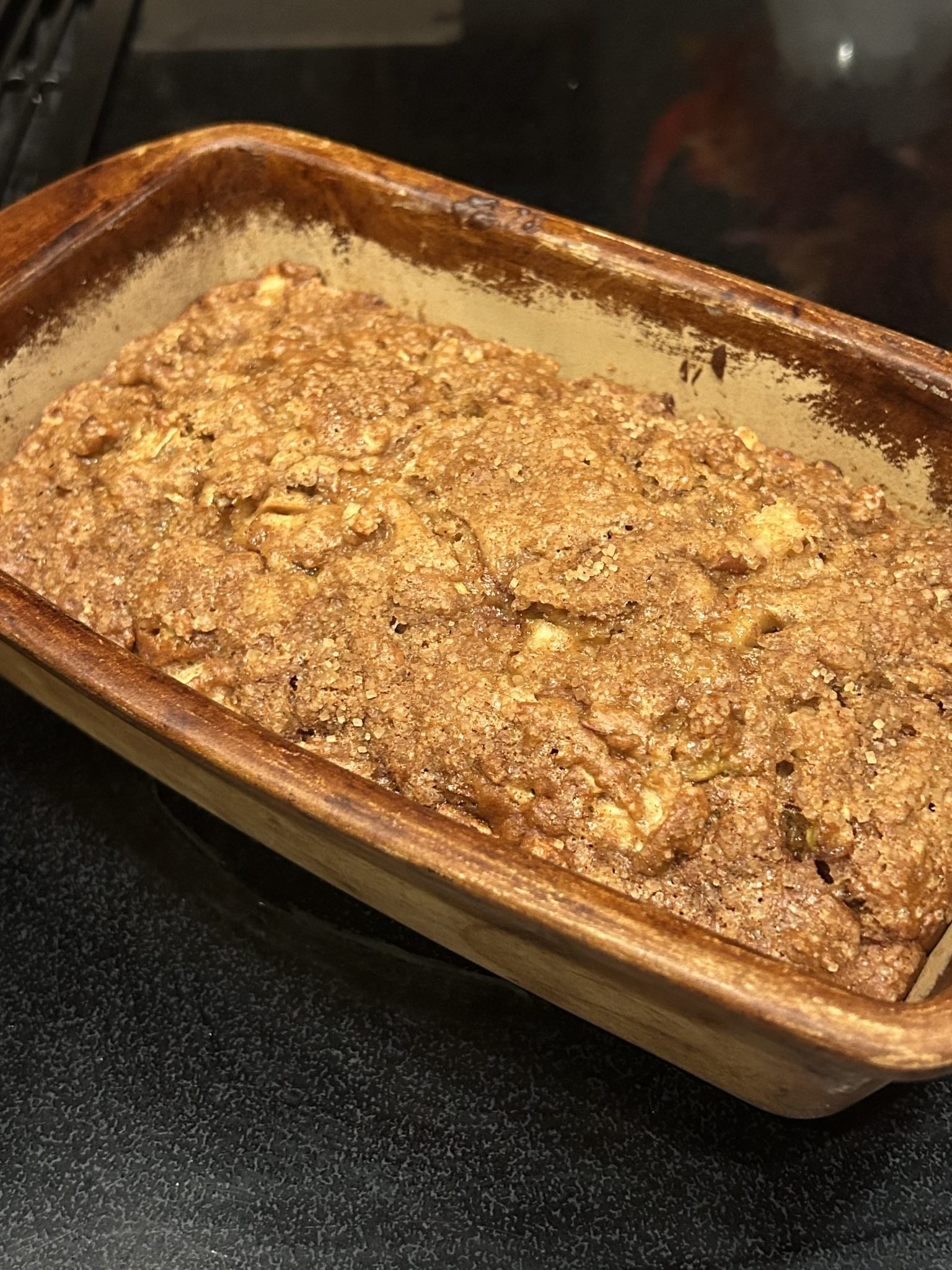 Freshly baked loaf of bread with a crumbly brown top in a rectangular ceramic baking dish.