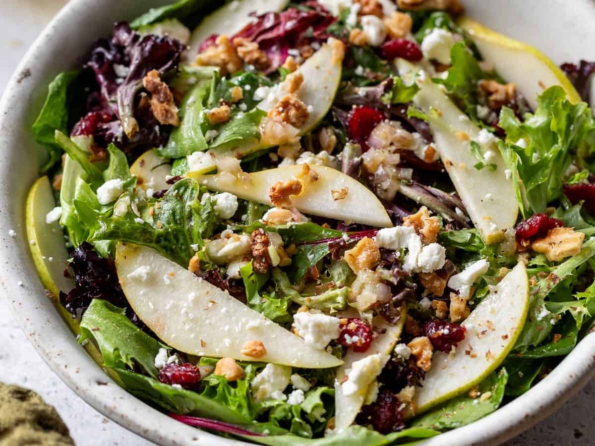 Pear salad in bowl with walnuts, feta, and cranberries