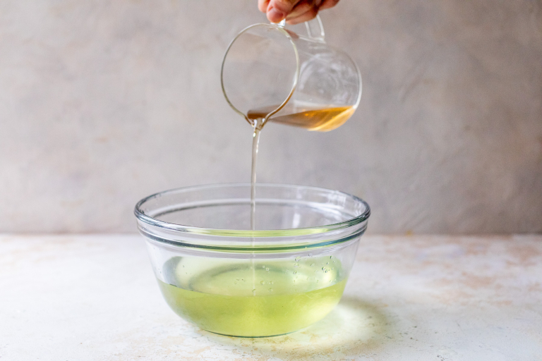 Pouring simple syrup into infused vodka to make limoncello