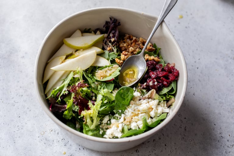 Drizzling vinaigrette onto pear salad