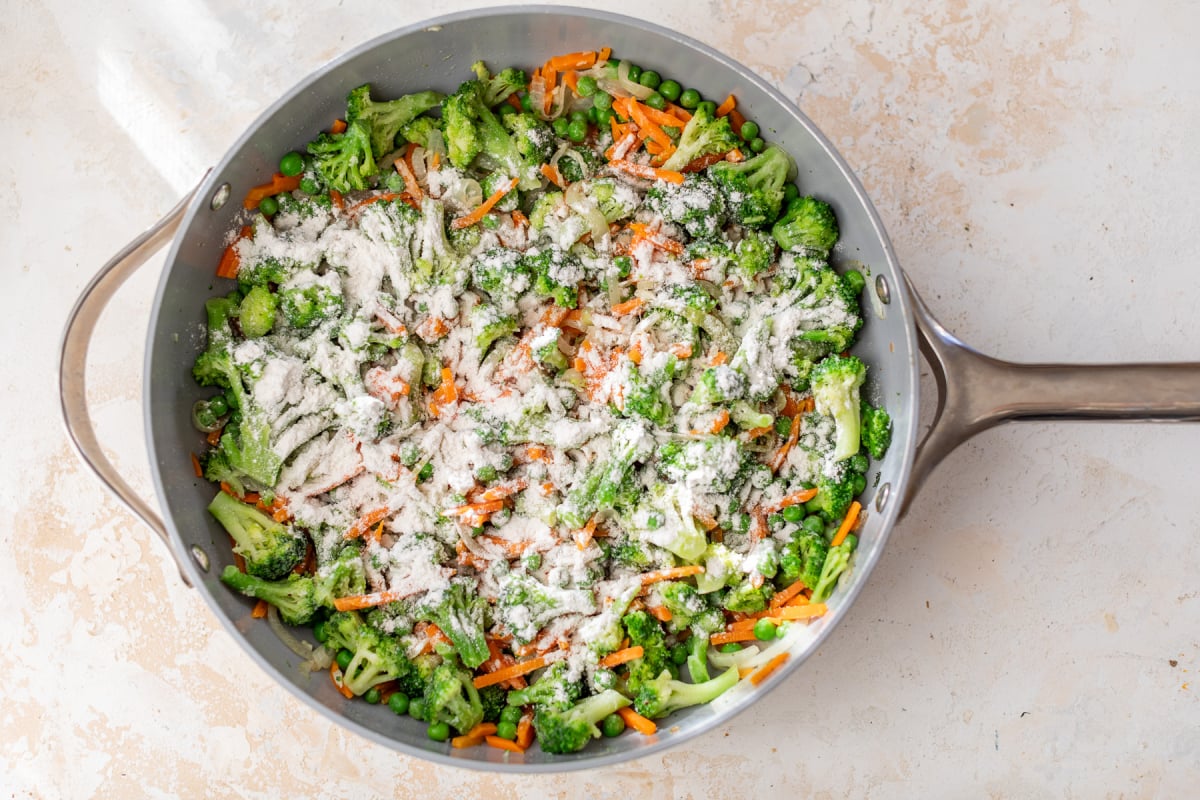 Flour sprinkled over vegetables in skillet