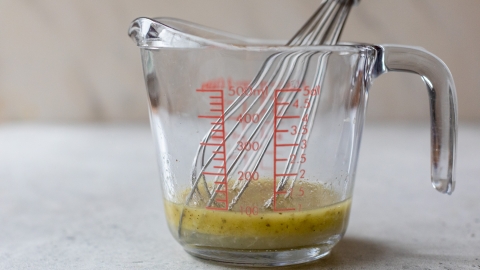 Lemon vinaigrette in liquid measuring cup with whisk