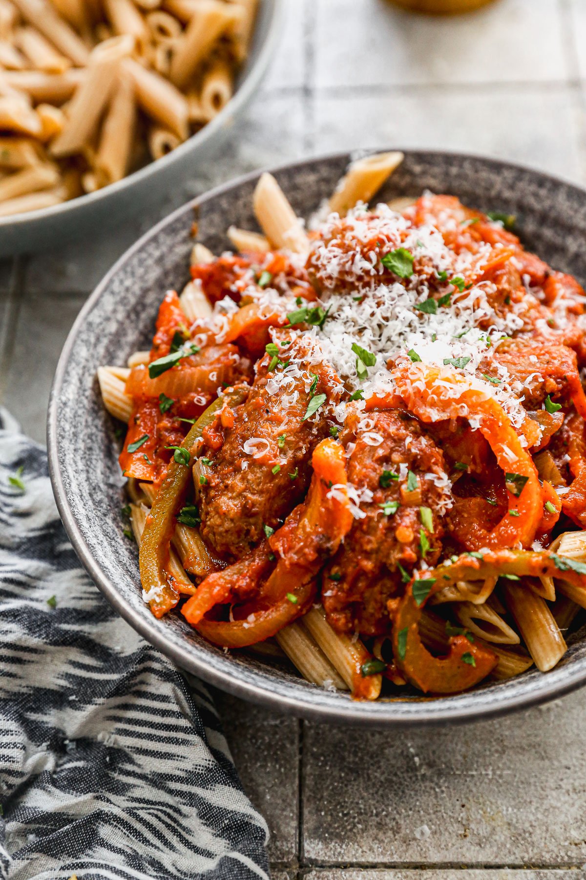 Slow cooker sausage and peppers served over bowl of pasta