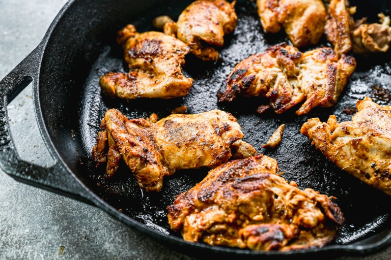 Greek chicken thighs cooking in skillet
