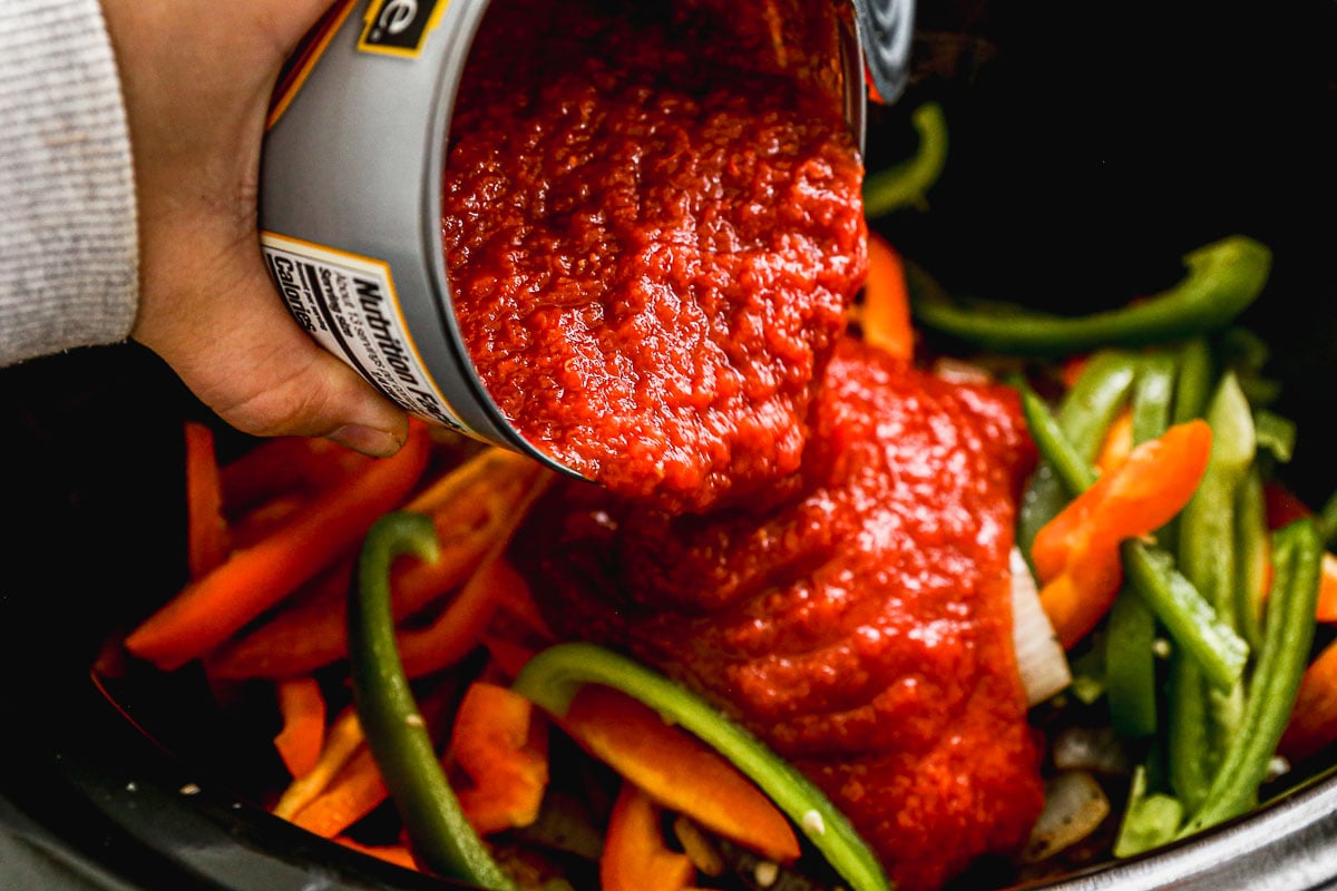 Pouring tomato sauce into slow cooker
