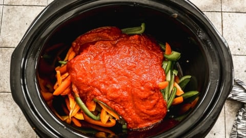 Sauce poured over peppers and sausage in crockpot