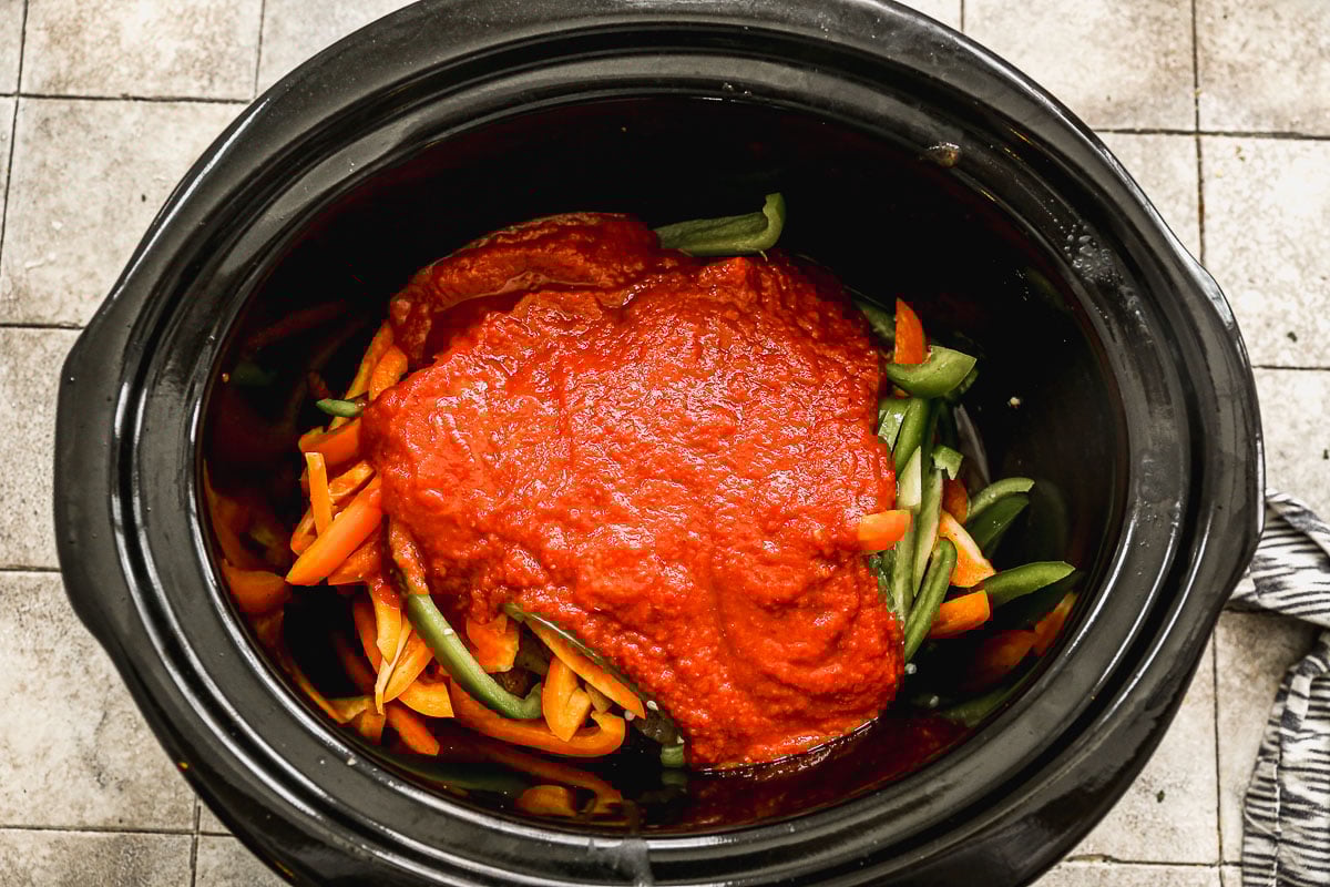 Sauce poured over peppers and sausage in crockpot