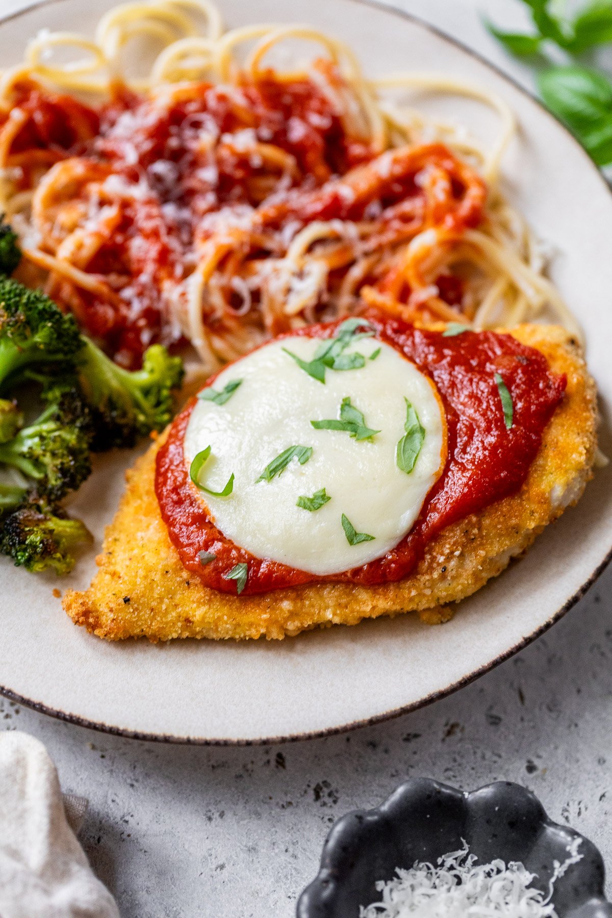 Air fryer chicken Parmesan on plate with spaghetti and broccoli.