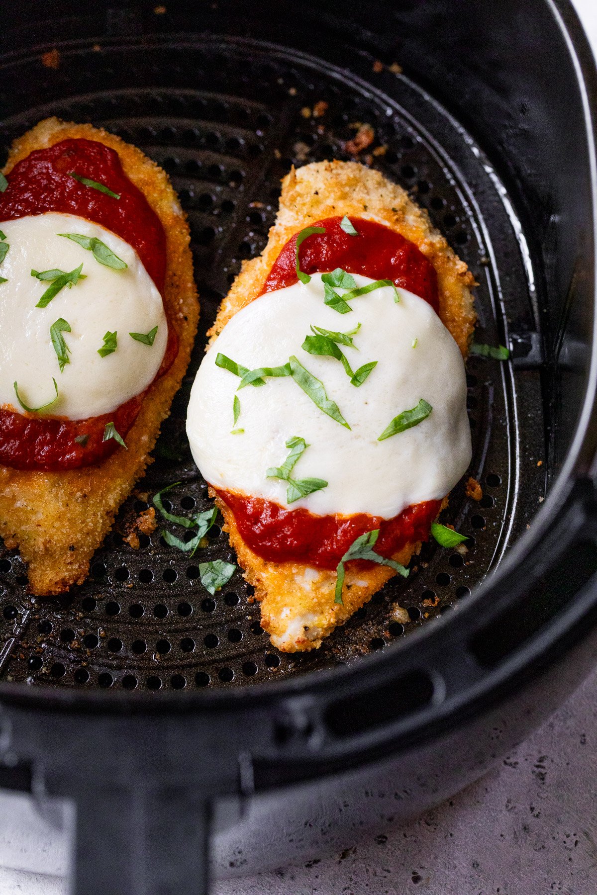 Air fryer chicken Parmesan in air fryer basket.