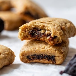 Two fig bars, one stacked on top of the other, with the top cookie showing a bite and fig filling inside.