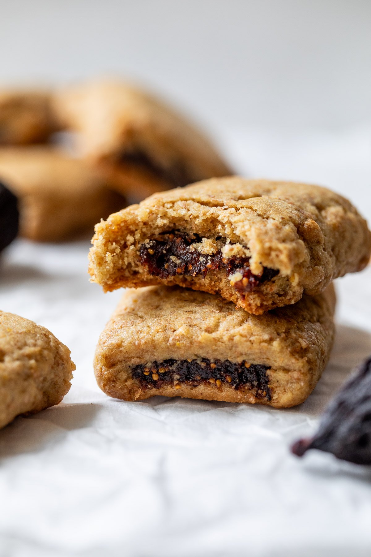 Two fig bars, one stacked on top of the other, with the top cookie showing a bite and fig filling inside.