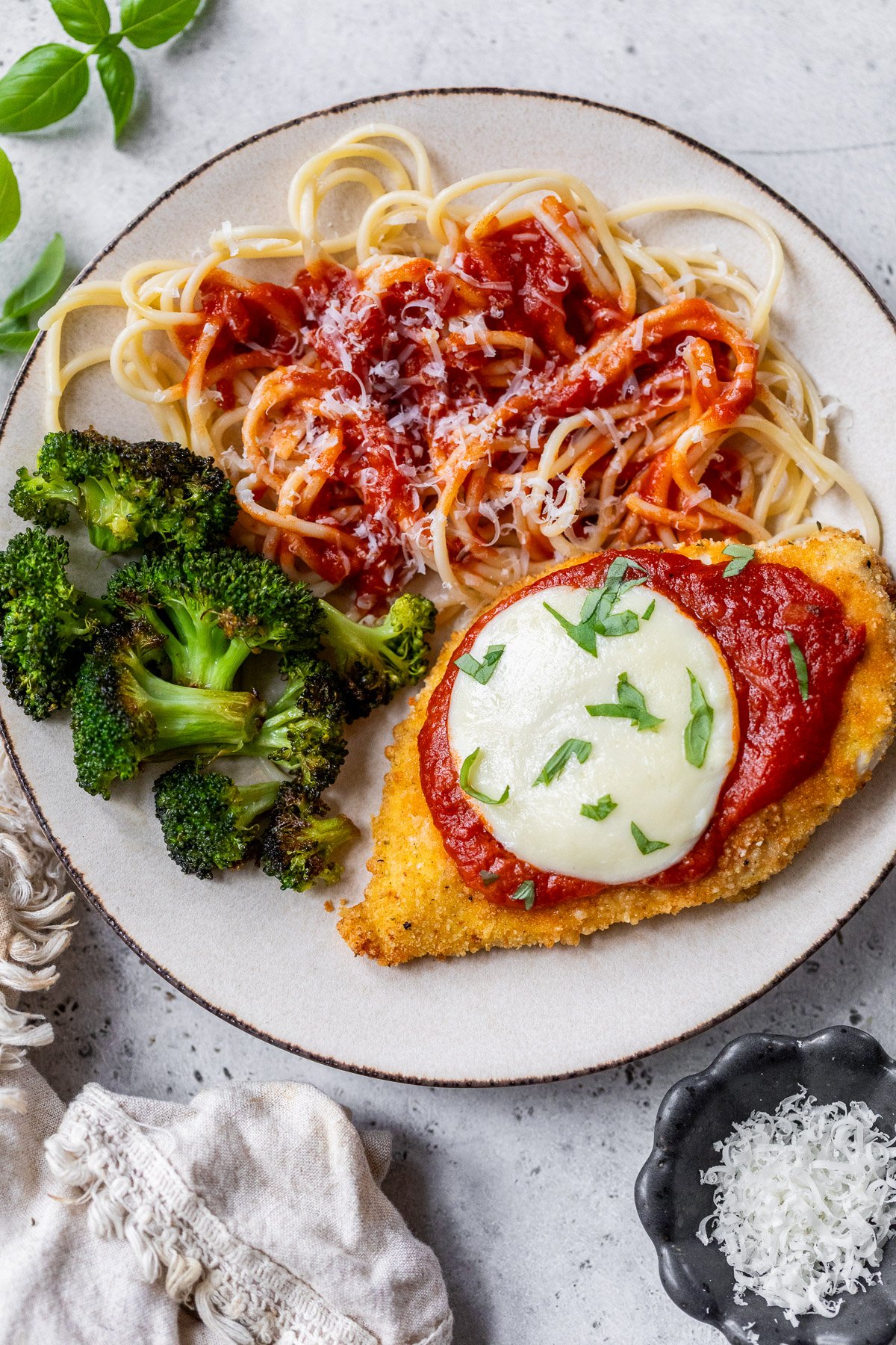 Air fryer chicken Parmesan on plate with spaghetti and broccoli.