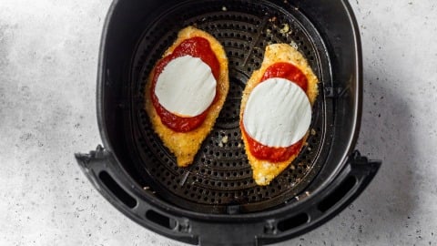 Marinara and mozzarella added to chicken Parmesan in air fryer.