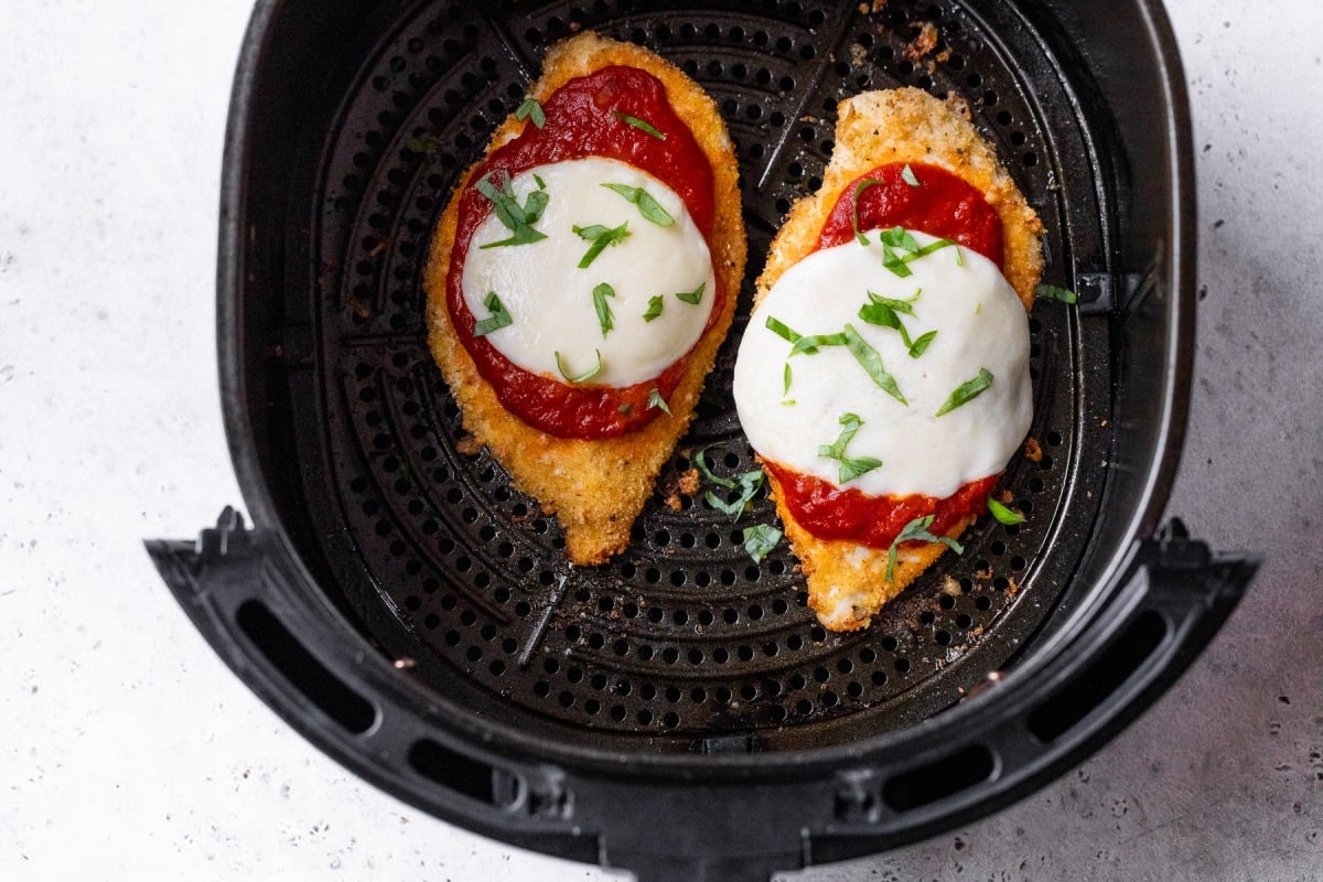 Chicken Parmesan in air fryer topped with basil.