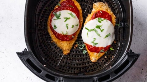 Chicken Parmesan in air fryer topped with basil.