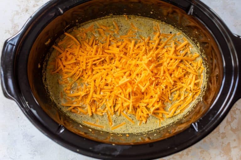 Shredded cheese added to crockpot for broccoli cheese soup.