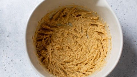 A white bowl filled with light brown fig bar dough sits on a light gray surface.