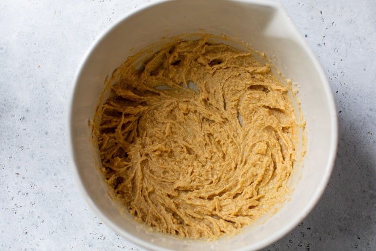 A white bowl filled with light brown fig bar dough sits on a light gray surface.