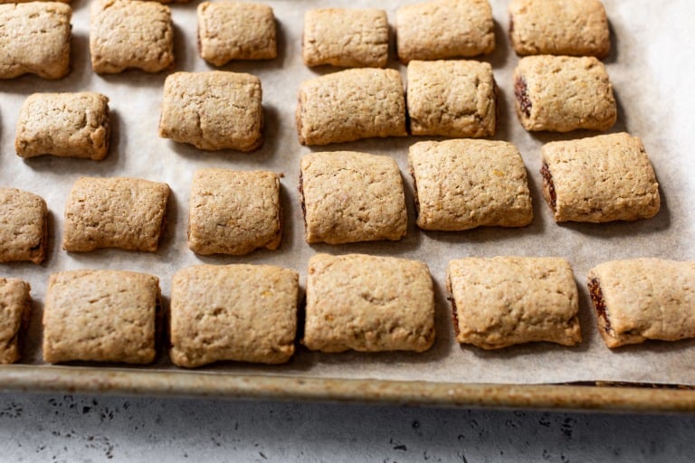 Rectangular fig bars arranged on a parchment-lined baking sheet.
