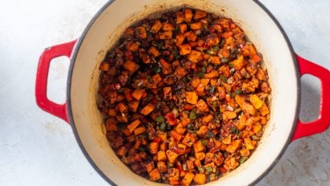 Spices and tomato paste added to Dutch oven with vegetables for chili.