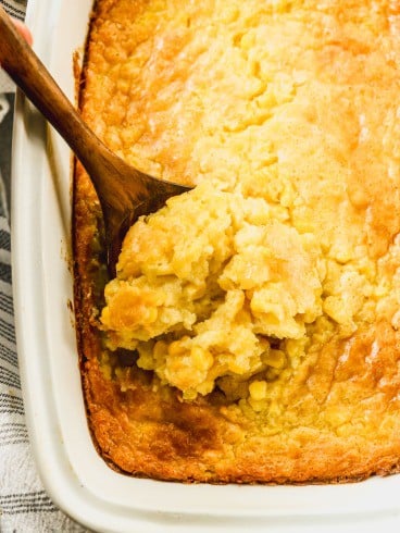 Scooping corn souffle from baking dish.