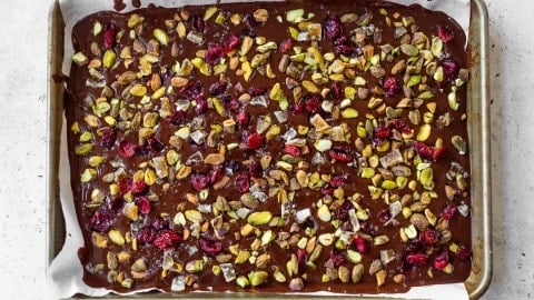 Pistachios, cranberries, candied ginger, and sea salt added to melted chocolate on sheet pan.