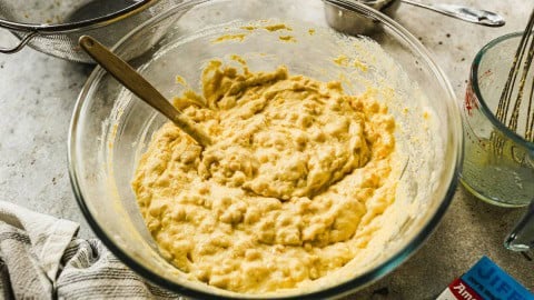 Stirring corn souffle mixture in glass bowl.