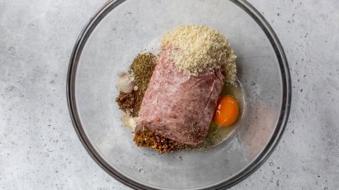 Ingredients for pork meatballs in glass bowl.