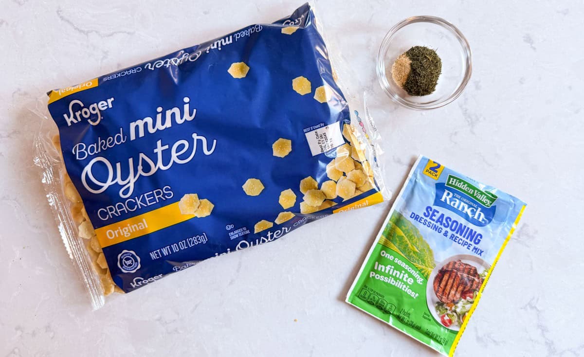 a bag of oyster crackers, ranch seasoning packet, and bowl with dill and garlic powder