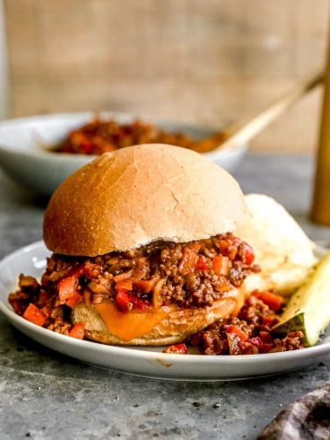 Crockpot sloppy joe on plate with pickle spear.