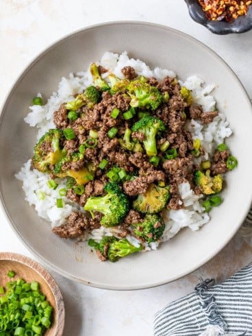 Bowl of rice topped with ground beef and broccoli stir fry.