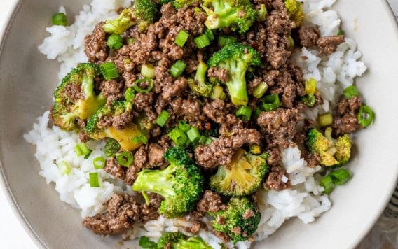 Bowl of rice topped with ground beef and broccoli stir fry.