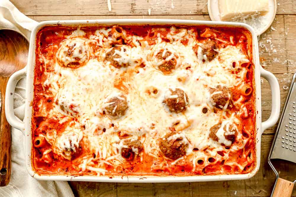 A casserole dish with baked meatball casserole, meatballs, and melted cheese on top, sitting on a wooden table.