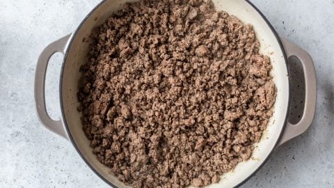 Cooked ground beef in a large, round pot on a light gray countertop, viewed from above.