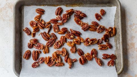 Candied pecans spread onto parchment-lined pan.