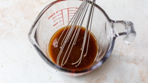 Whisk in liquid measuring cup with balsamic vinaigrette.