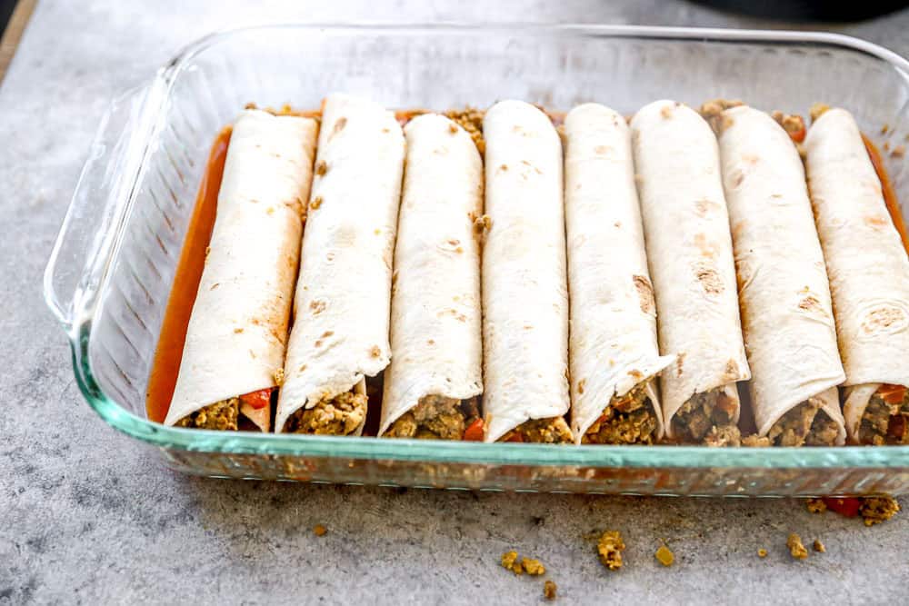 Rolled up breakfast enchiladas in glass baking dish.