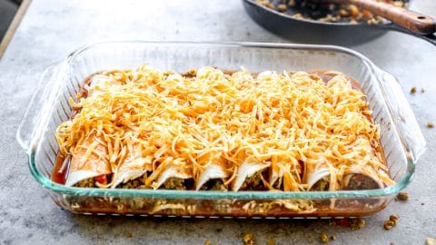 Shredded cheese added to breakfast enchiladas.
