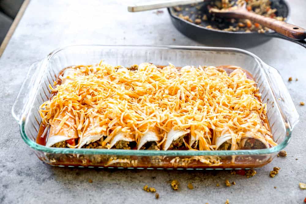 Shredded cheese added to breakfast enchiladas.