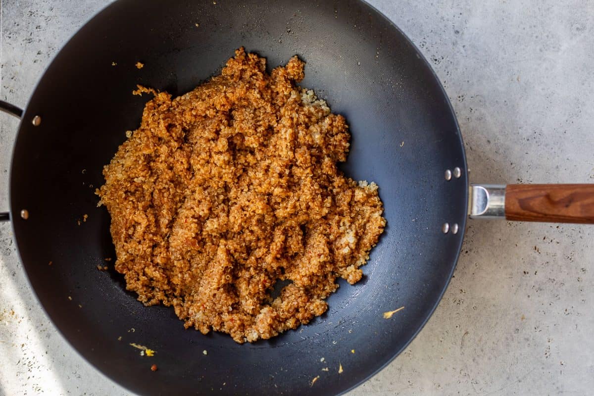 A black pan with quinoa fried rice in it.